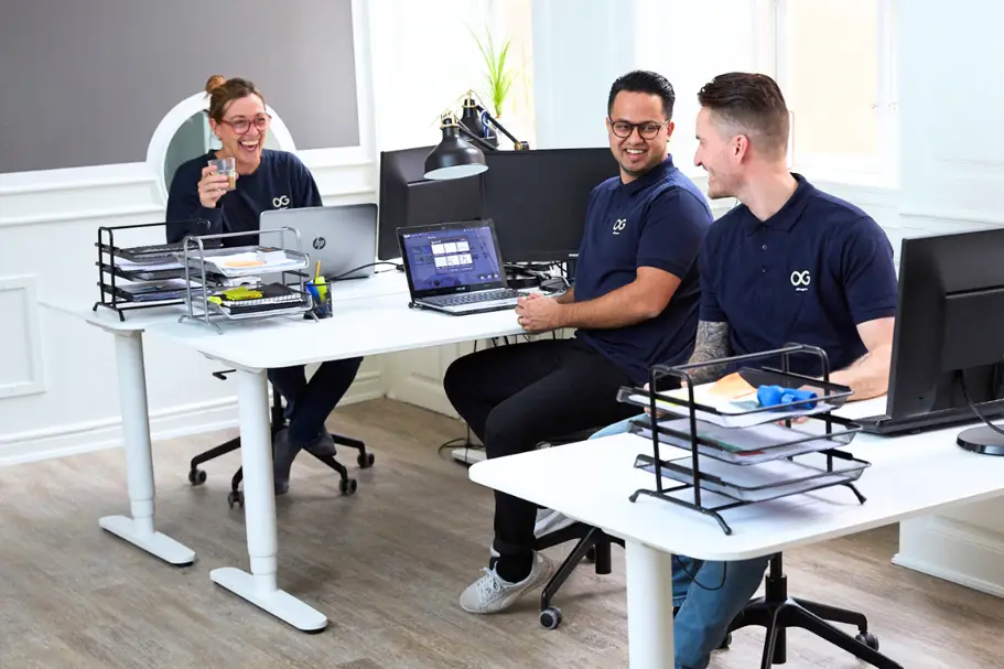Men and women sitting at their desks laughing in conversation at Officeguru